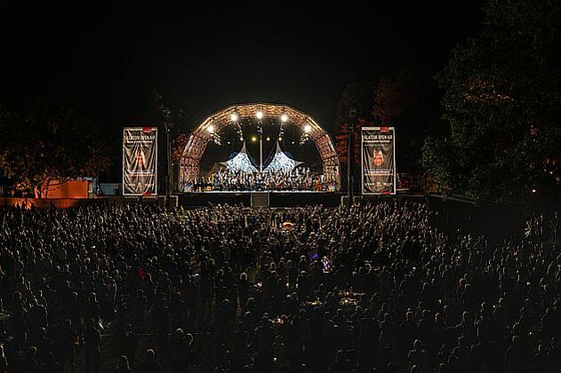 Konzertbühne bei Nacht mit Tausenden Zuschauern davor.